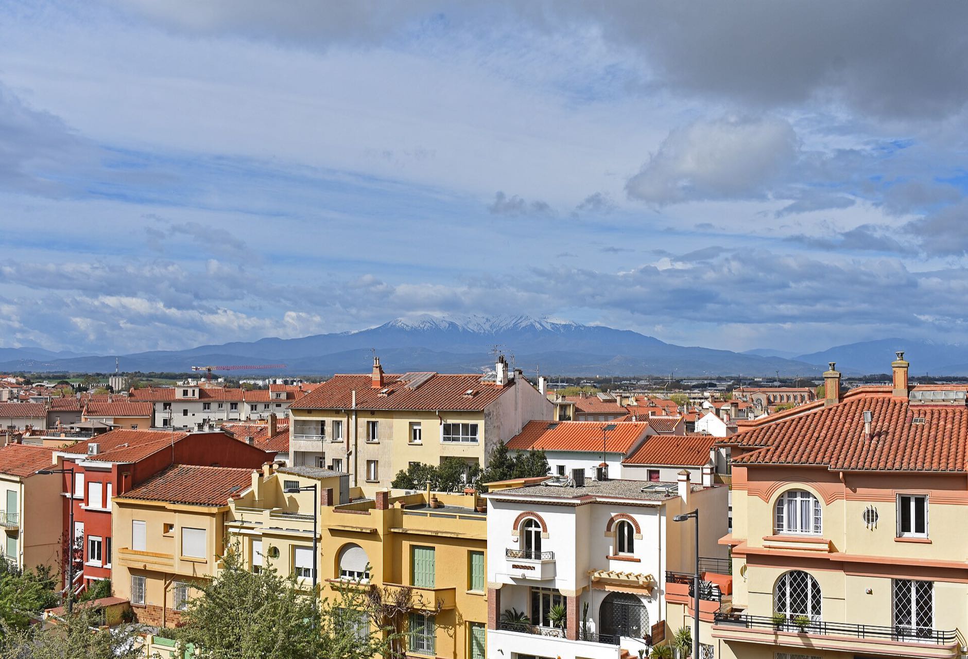 Maisons aux façades colorées et toits de tuiles à Perpignan, le Canigou au fond
